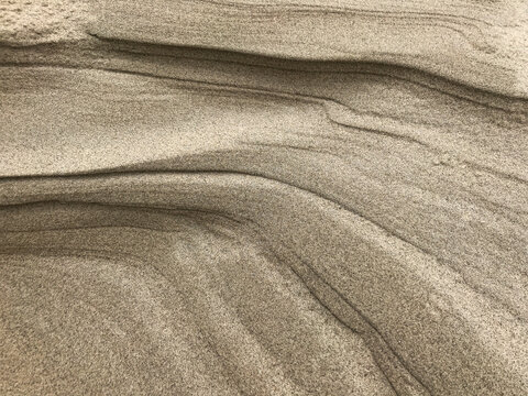 View of layers of sand sculpted by wind and water, creating a textured landscape of natural patterns and subtle color variations, De Cocksdorp, Noord-Holland, Netherlands.