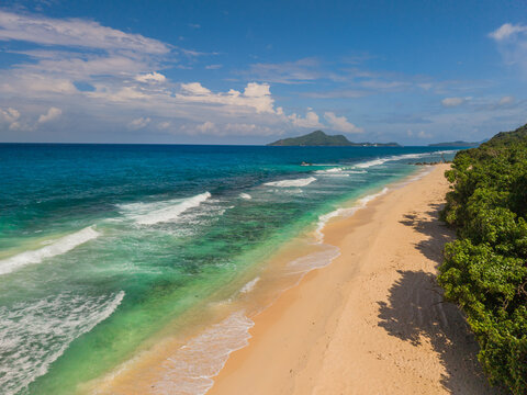 Aerial view of the turquoise sea meeting the sandy shore, framed by lush greenery, La Retraite, Mahe Island, Seychelles.