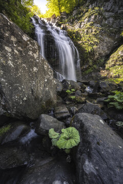 View of cascading waterfall over rocky terrain, sunlit foliage peeks through, creating a serene, natural scene, Lizzano In Belvedere, Emilia-Romagna, Italy.