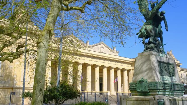 Historic neoclassical building with columns and bronze statue in Bordeaux