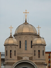 Golden domes topped with ornate metallic crosses on an Eastern Orthodox church architecture against an overcast sky. © Dan