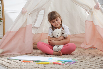Little girl with toy sheep near wigwam at home © New Africa