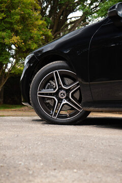 Black Mercedes CLA 200 front wheel close up, Luxury sedan coupe on pavement near trees