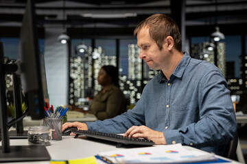 Fototapeta premium Professional architectural designer configures a floor plan on dual monitors, utilizing computer aided design tools. Young man uses digital rendering and interior decoration remodeling.