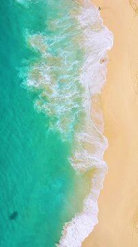 Aerial drone footage of big waves crashing on a sandy tropical beach. Vertical fullHD video. Top view of powerful ocean surf and blue sea water. Perfect for mobile content, travel relaxation.