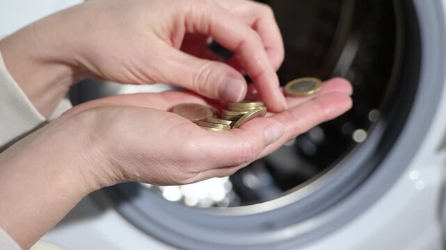 Managing household expenses and savings. Female hands carefully counting euro coins in front of an open washing machine, illustrating the concept managing household expenses and savings