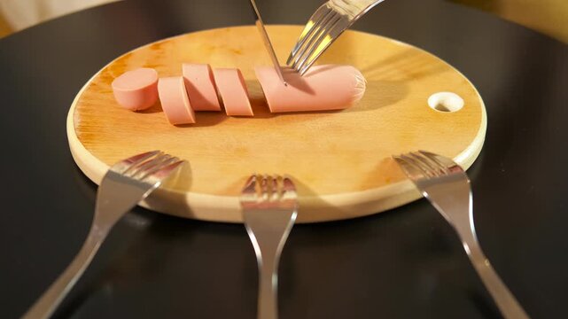 Person slicing sausage on wooden board. Person using a knife and fork to slice a sausage on a wooden cutting board, with other forks around, symbolizing competition or the division of resources