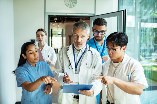 Doctors and nurses discussing patient chart in hospital corridor