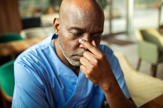 Tired healthcare worker rubbing eyes in hospital break room
