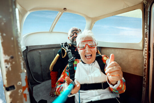 Happy older adults ready for tandem skydive inside small airplane