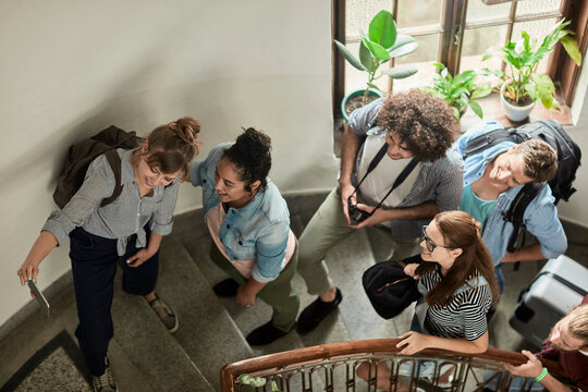 Group of young travelers taking a selfie on hostel staircase