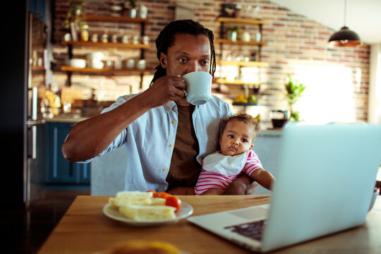 Father working from home with baby in kitchen