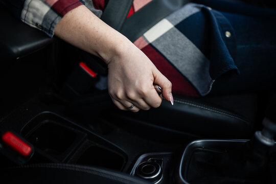 Hand engaging parking brake lever in car interior
