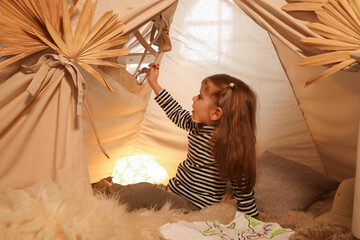 Little girl with drawing of map and toy giraffe near wigwam at home © New Africa
