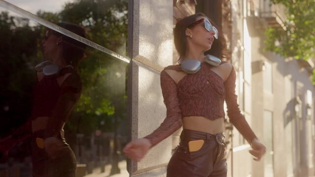 Happy stylish woman dancing in city street