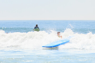 Obraz premium A surfer falls into the ocean as their blue surfboard splashes through a wave, capturing an action-packed surfing wipeout moment. Stock photo