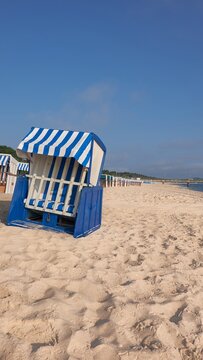 Strandkorb on Rugen beach with blue striped canopy and empty seating near dunes