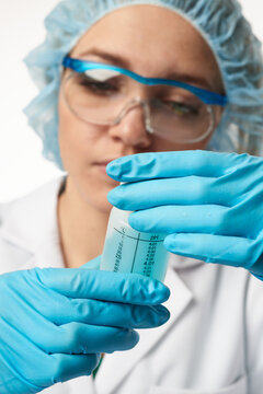 Young european female scientist handling conical centrifuge tube in laboratory wearing protective gear