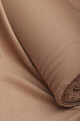 Fototapeta premium High-quality close-up of fabric roll of 100% camel brown cashmere fabric. Soft, luxury textile texture with elegant folds, ideal for high-end fashion, winter coat design, and premium apparel concepts.
