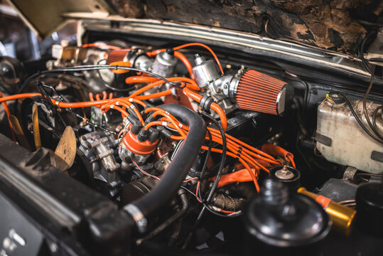 Detailed view of a classic car engine with orange spark plug wires and air filter