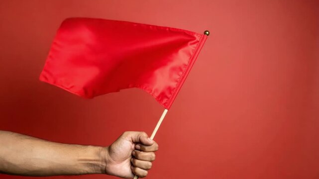 Hand holding a vibrant red flag against a matching red background