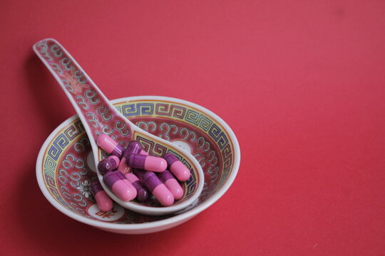 Capsulas para la salud sobre cer&aacute;mica japonesa con un fondo rojo.