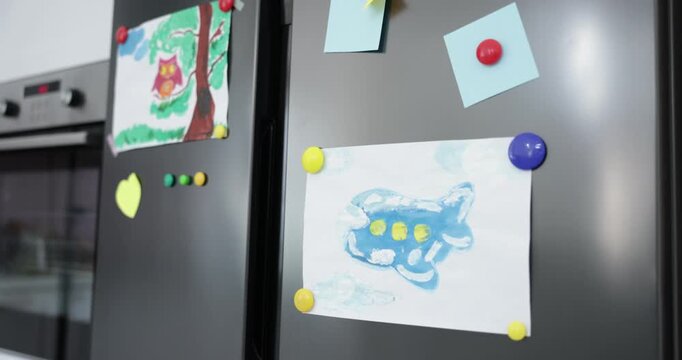 Refrigerator with child's drawings and magnets indoors, closeup