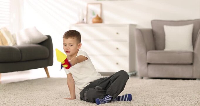 Little boy playing with handmade toy rocket on floor indoors