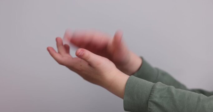 Child clapping hands on light grey background, closeup