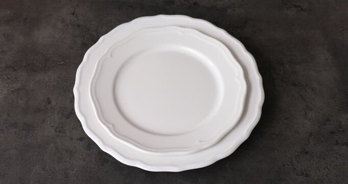 Woman putting plates and cutlery on black table, closeup
