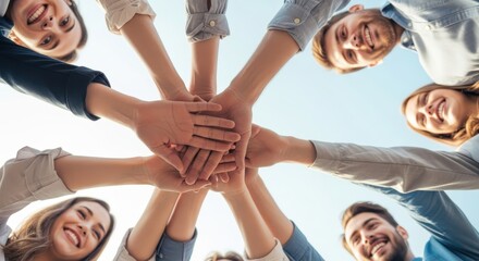Obraz premium Diverse group of happy young people joining their hands together in a circle to show unity and teamwork.