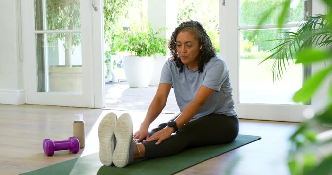 African American woman in gymwear seeing mat sliding, reaching shoes, stretching at home