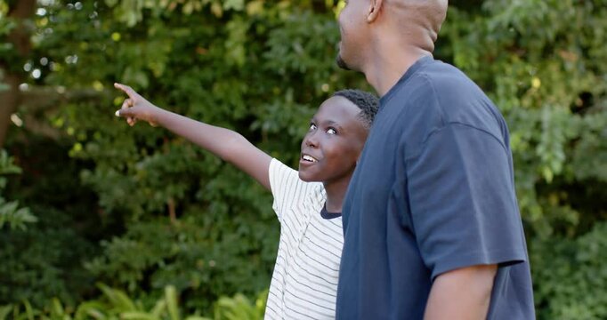 Pointing son talking while dad watching in park, pointing finger, navy and white striped tees