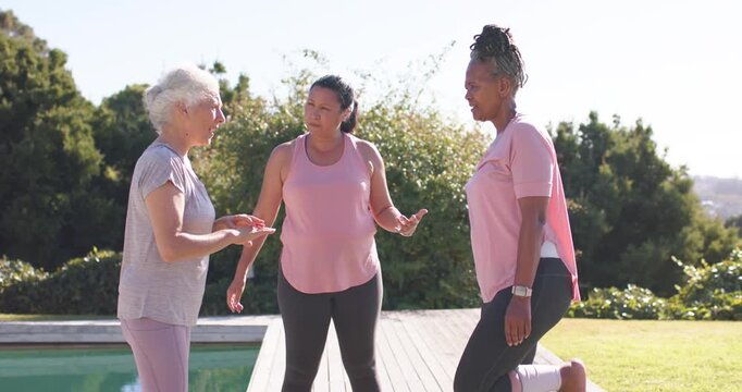 Diverse women stretching on deck by pool Senior White talking causing center Asian showing stretch