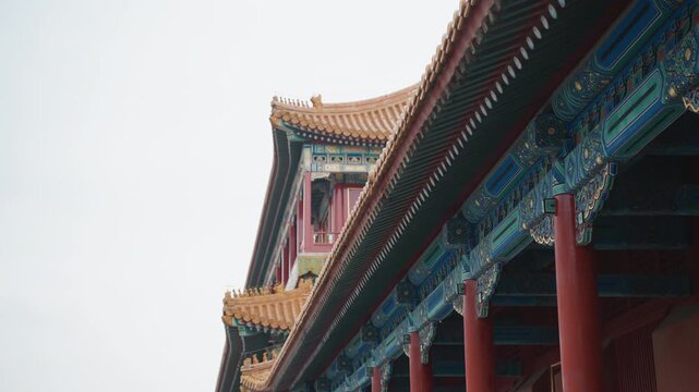 Ornate temple roof and columns framed in closeup, colorful gilding and carved brackets, red pillars and golden tiles, calm overcast sky, emphasis on pattern, symmetry and craftsmanship, mood