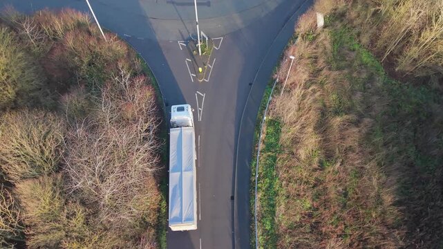 Aerial Roundabout View With Truck Negotiating Tight Turn In Rural Junction, Articulated Trailer Swings Across Lanes, Winter Trees Lining Roadside, Oncoming Car Yielding, Highangle Drone