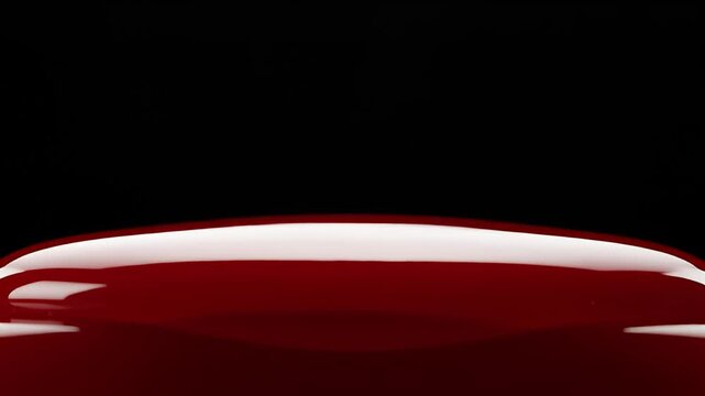 Glossy red liquid forms a sculptural shape on black background