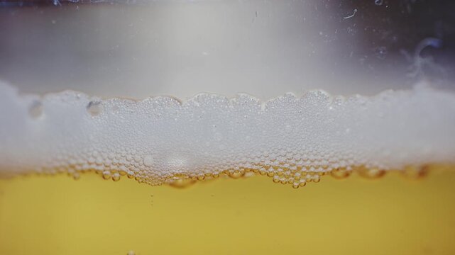 Extreme close up of beer foam and bubbles forming on top of a drink