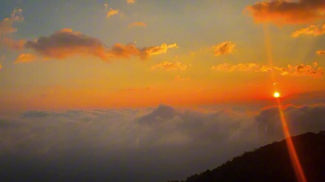 A stunning golden sunrise breaking over a vast sea of clouds in Yunnan's Ailao Mountains. Rich orange and yellow hues paint the morning sky in this majestic landscape.