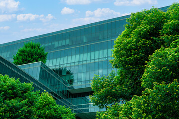 Eco-friendly building in the modern city. Sustainable glass office building with trees for reducing heat and carbon dioxide. Office building with green environment. Corporate building reduce CO2. © Fahroni
