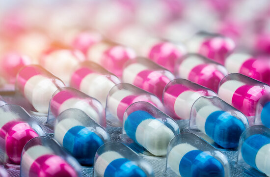 Closeup pink-white and blue-white antibiotics capsule pills in blister pack. Antimicrobial drug resistance. Pharmaceutical industry. Global healthcare. Pharmacy background. Amoxicillin capsule pills.