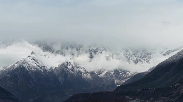 Dynamic 4K time-lapse showing a vast sea of clouds moving like waves over jagged Himalayan snow peaks in Tibet, bathed in golden morning light.