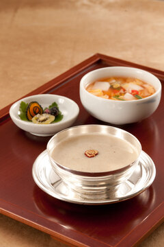 Korean Traditional Health Food Perilla Seed Porridge Deul깨juk and Water Kimchi on Red Lacquer Tray