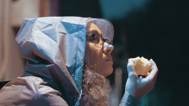 Night city woman sampling treat. City scene captures woman savoring pastry in nighttime ambiance. An intimate night shot revealing woman tasting pastry with reflective mood and soft focus