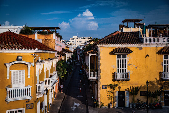 Rua estreita com pr&eacute;dios hist&oacute;ricos e c&eacute;u azul com nuvens