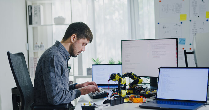 Young adult male freelance developer typing write prompt AI bot app program nomad terminal with coding at office. Artificial intelligence dashboard, robotics, user interface, machine learning concept.