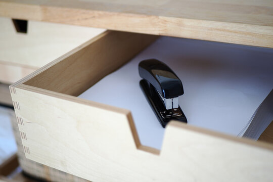 Drawer holds a stapler and white paper in office space