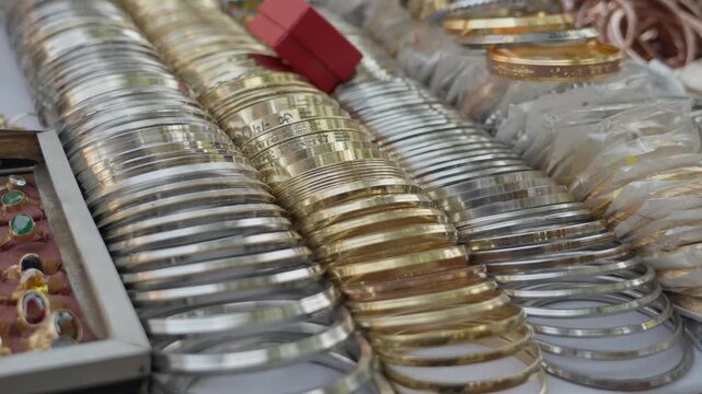 Close up of gold and silver bangles, bracelets and gemstone rings at a street stall in Kolkata, India. Perfect for travel and cultural documentaries.
