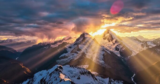 Aerial drone view of snow-capped mountains at sunset with golden sunbeams