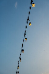 Obraz premium String of small lights glowing bulbs illuminating a twilight sky.